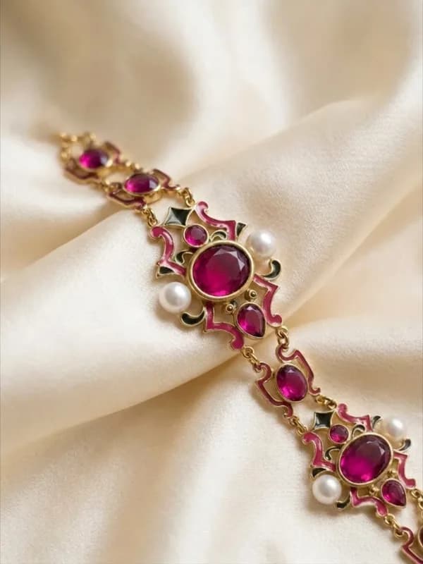 Pulsera Reina dorada de placas caladas con piedras fucsia, perlas y esmalte, sobre seda marfil