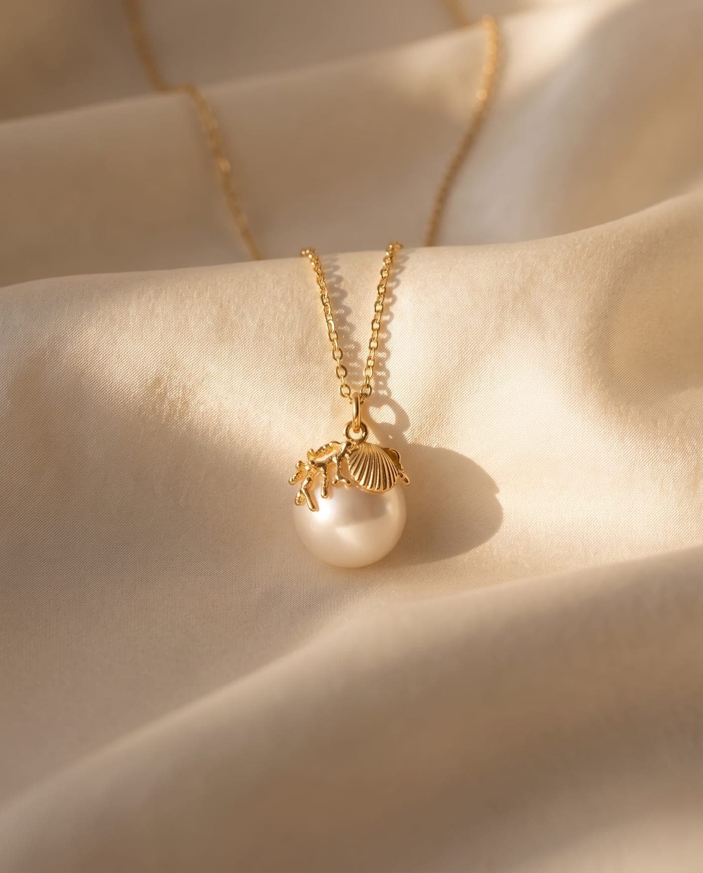 Colección Colección Concha: joya bañada en oro de la línea sobre seda crema, a la luz cálida