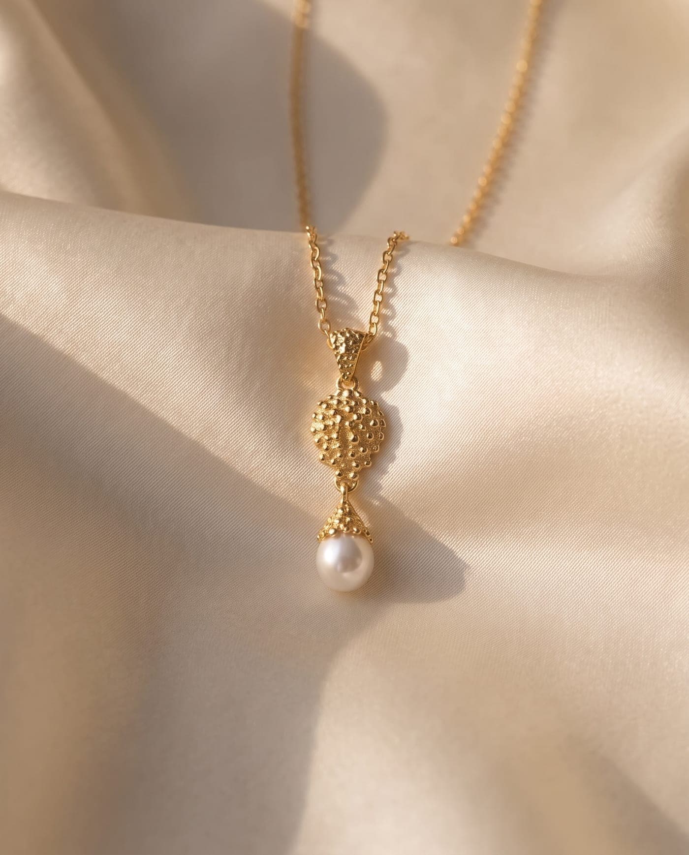 Colección Colección Constelación: joya bañada en oro de la línea sobre seda crema, a la luz cálida