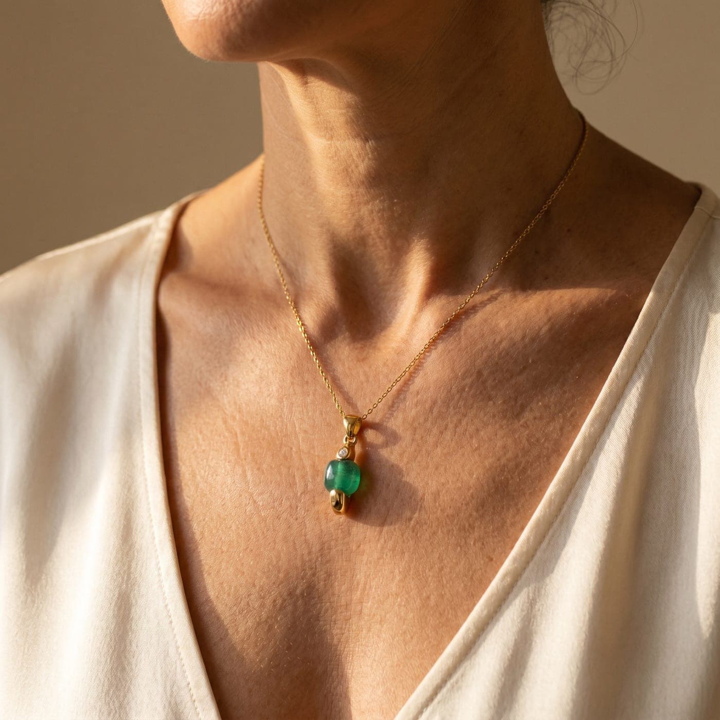 Colección Colección Gemma: joya bañada en oro de la línea sobre seda crema, a la luz cálida