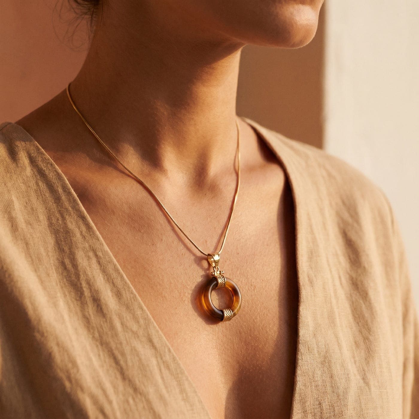 Colección Colección Órbita: joya bañada en oro de la línea sobre seda crema, a la luz cálida